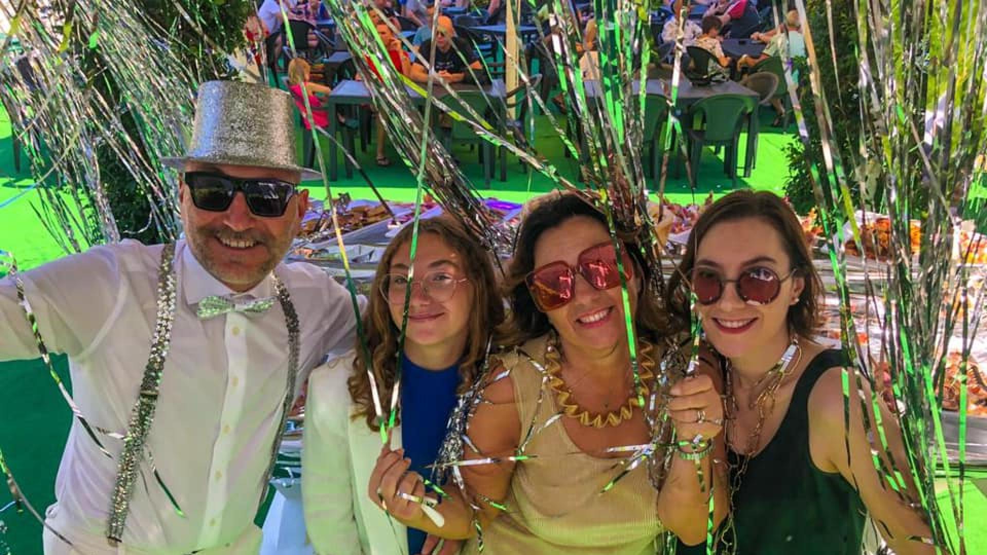 Four smiling people celebrate joyfully amidst sparkling decorations.