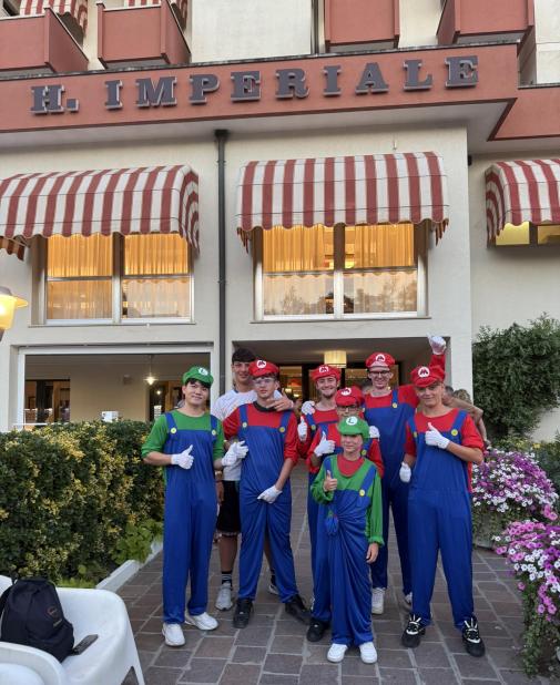Happy group in Mario and Luigi costumes outside a hotel.
