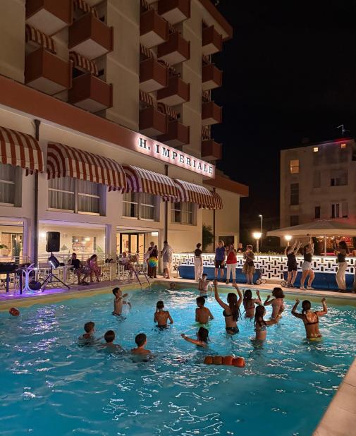 Lively night pool, children joyfully playing, festive and vibrant atmosphere.
