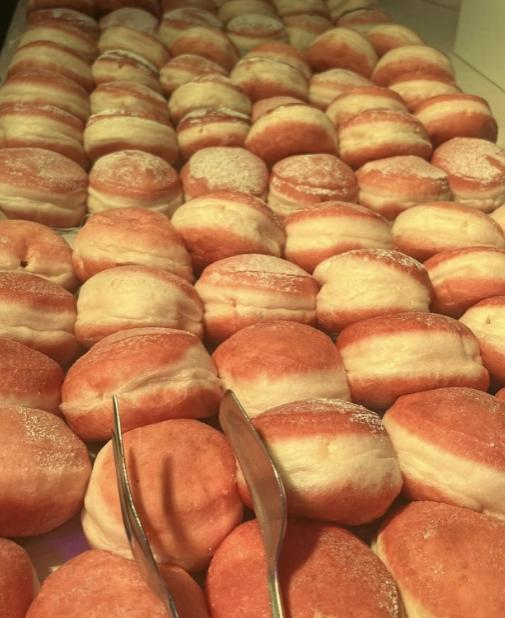Rows of soft, sugary pink donuts evoke sweetness and abundance.