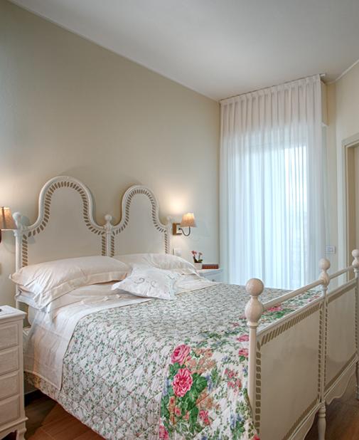 Camera luminosa con letto bianco, carta da parati tropicale e quadro rilassante.