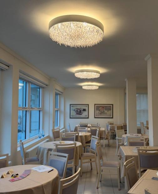 Sala elegante con lampadari scintillanti, tavoli apparecchiati e atmosfera accogliente.